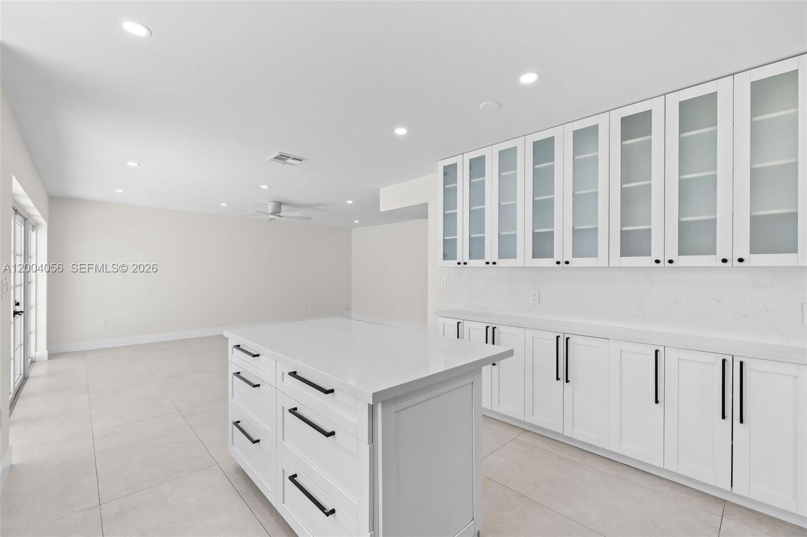 9547 Southwest 146th Place Miami, FL 33186 - Photo 16 of 40 a hall with kitchen island white cabinets and a refrigerator