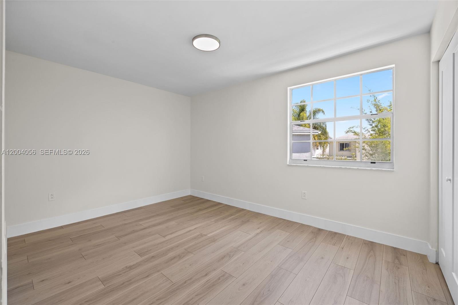 9547 Southwest 146th Place Miami, FL 33186 - Photo 27 of 40 a view of an empty room with wooden floor and a window