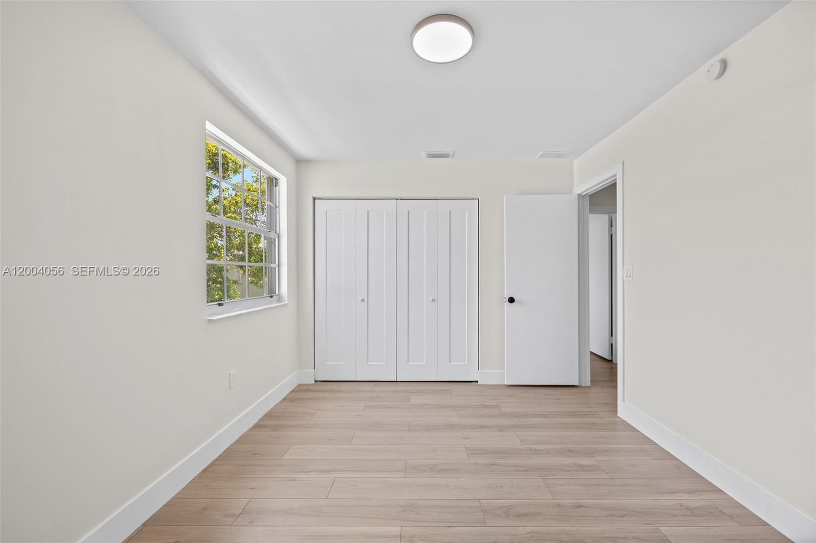 9547 Southwest 146th Place Miami, FL 33186 - Photo 28 of 40 a view of an empty room with wooden floor and a window