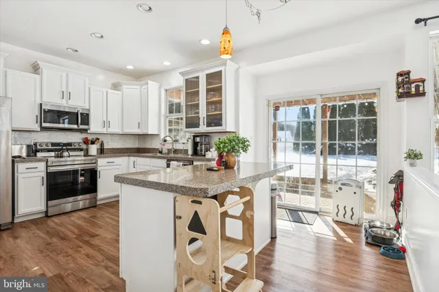 a kitchen with stainless steel appliances granite countertop a stove top oven a sink a dining table and chairs