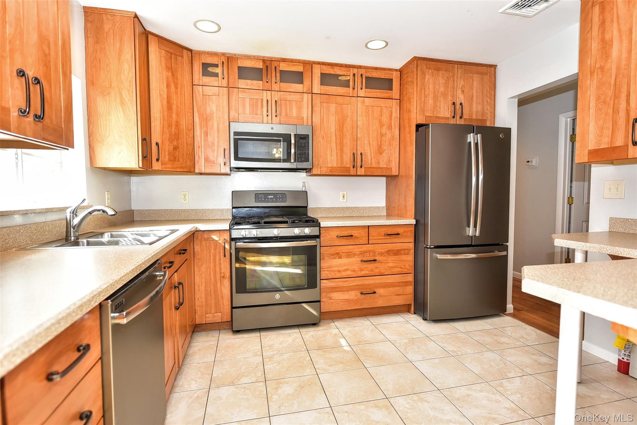 33 Hillcrest Road Suffern, NY 10901 - Photo 13 of 39 Kitchen with appliances with stainless steel finishes, glass insert cabinets, light tile patterned flooring, brown cabinetry, and recessed lighting