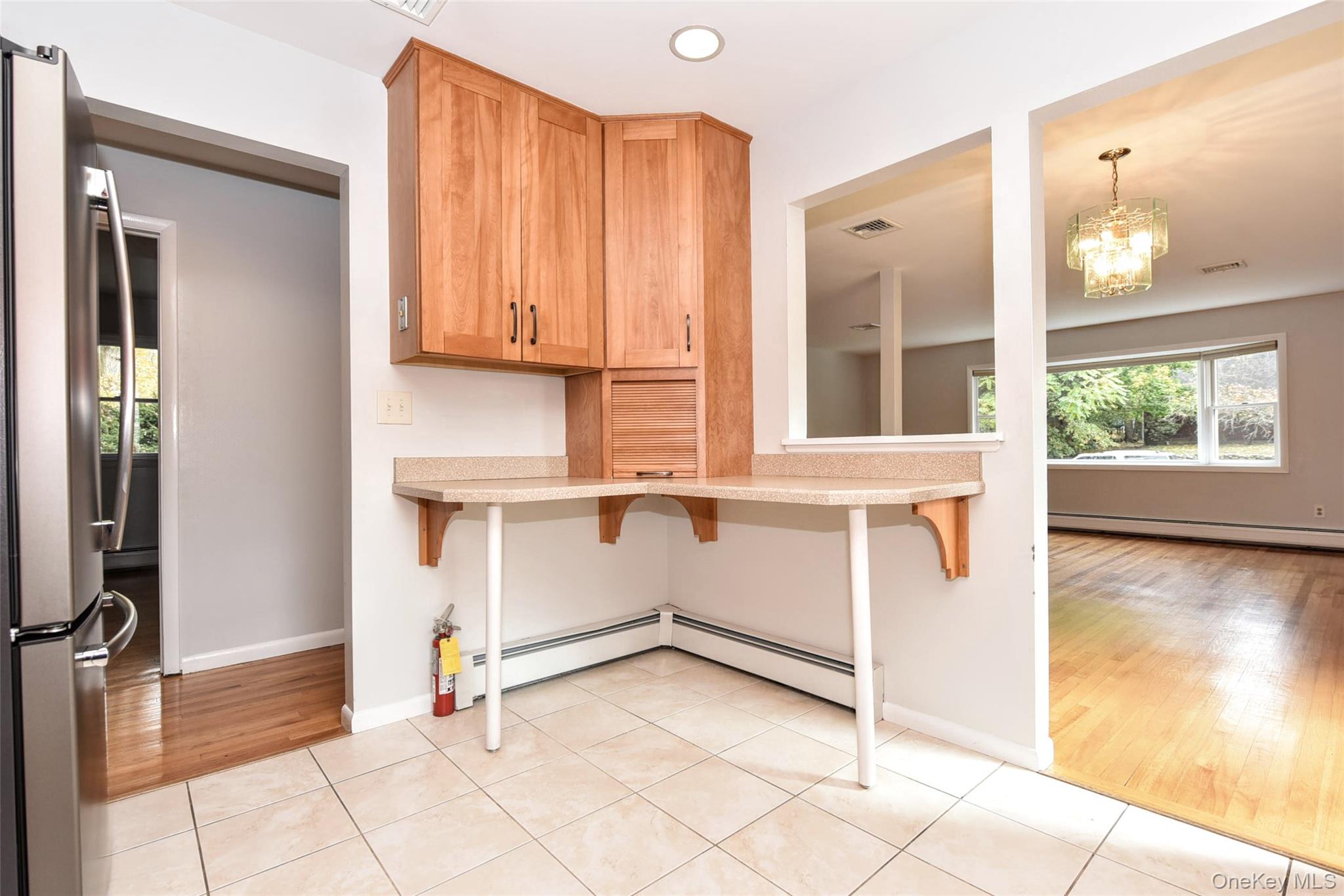 33 Hillcrest Road Suffern, NY 10901 - Photo 15 of 39 Kitchen with light tile patterned floors, freestanding refrigerator, a breakfast bar area, a baseboard radiator, and a chandelier