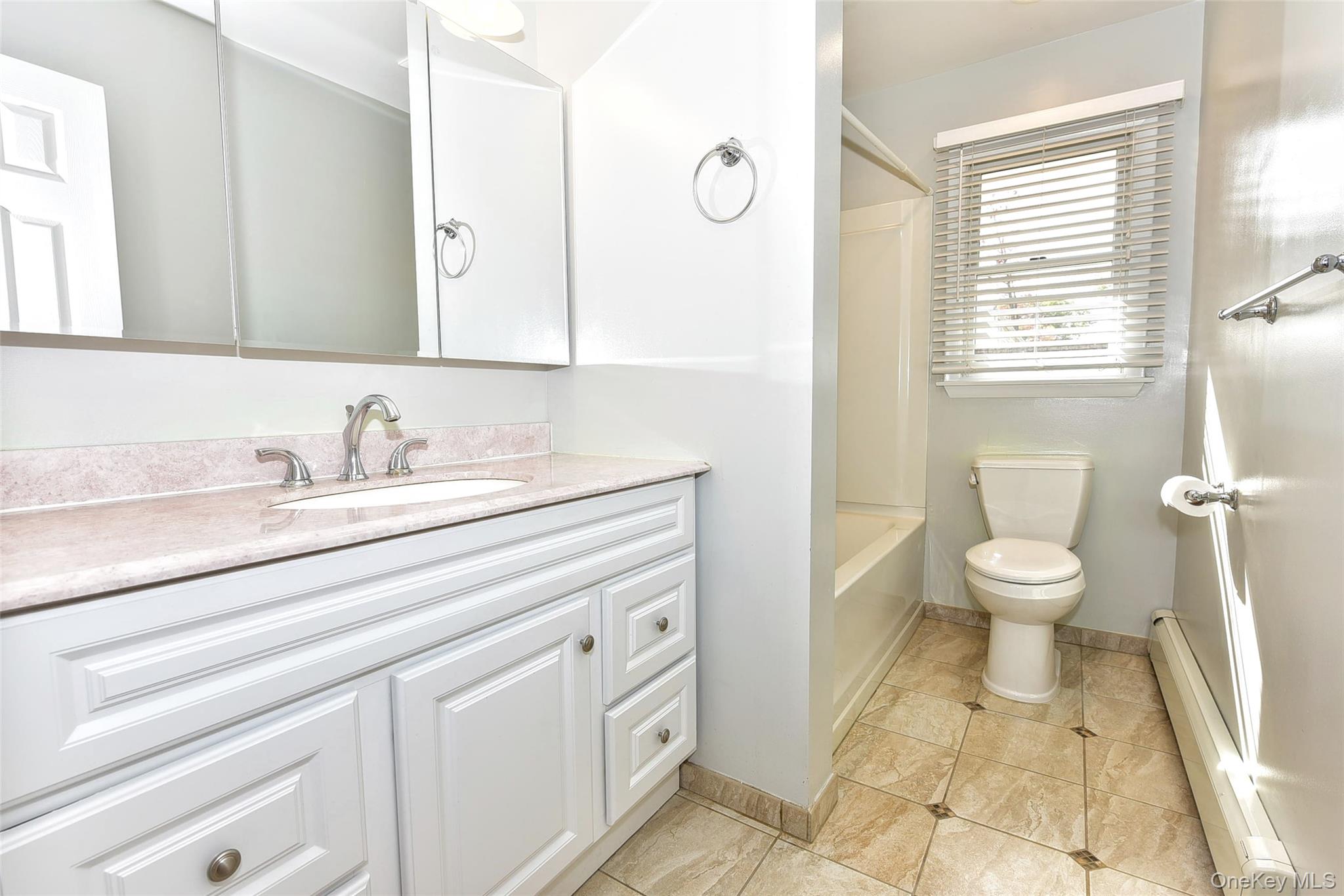 33 Hillcrest Road Suffern, NY 10901 - Photo 19 of 39 Full bathroom with a baseboard heating unit, vanity, bathing tub / shower combination, and light tile patterned flooring