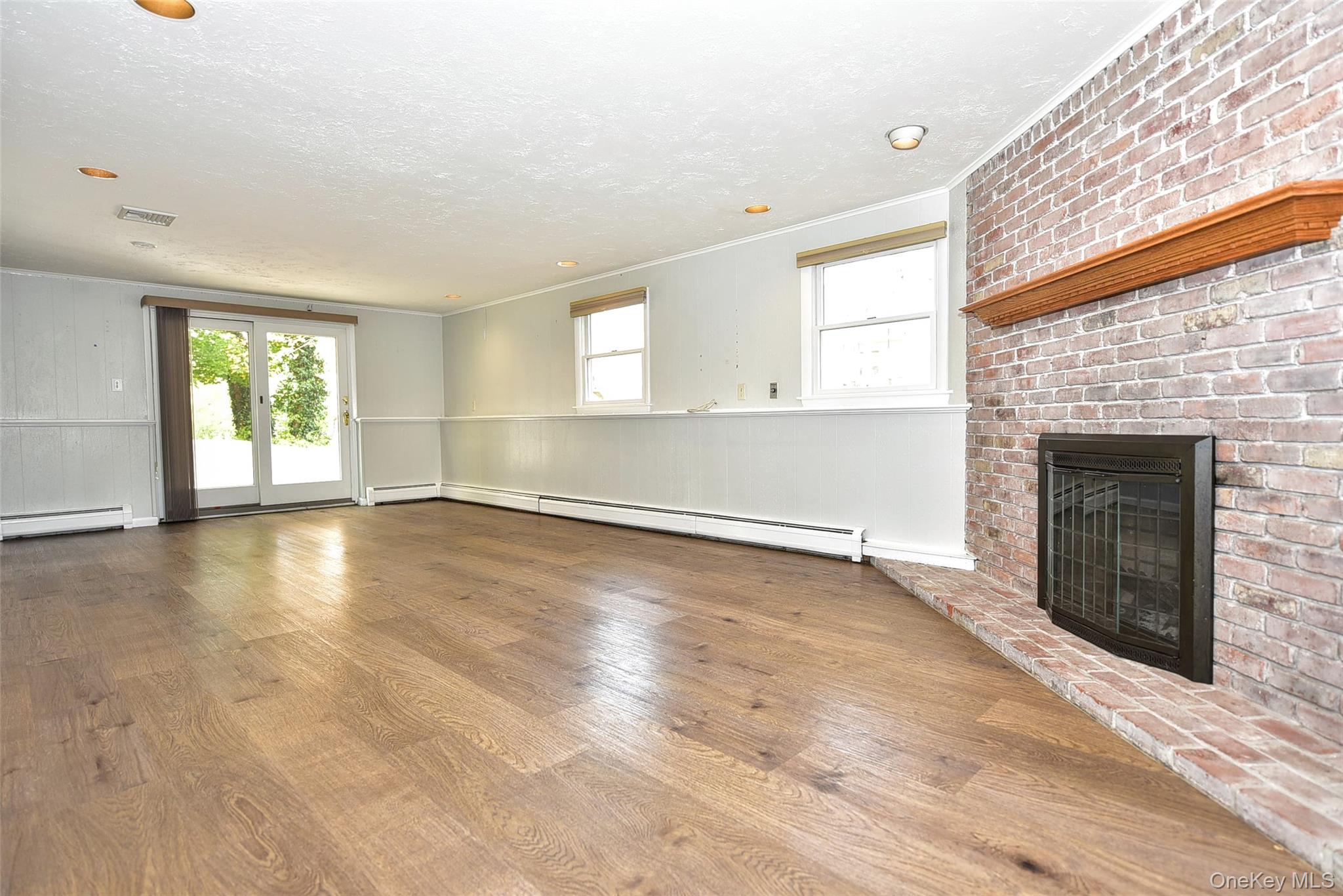 33 Hillcrest Road Suffern, NY 10901 - Photo 21 of 39 Unfurnished living room with crown molding, wood finished floors, a fireplace, plenty of natural light, and a baseboard radiator