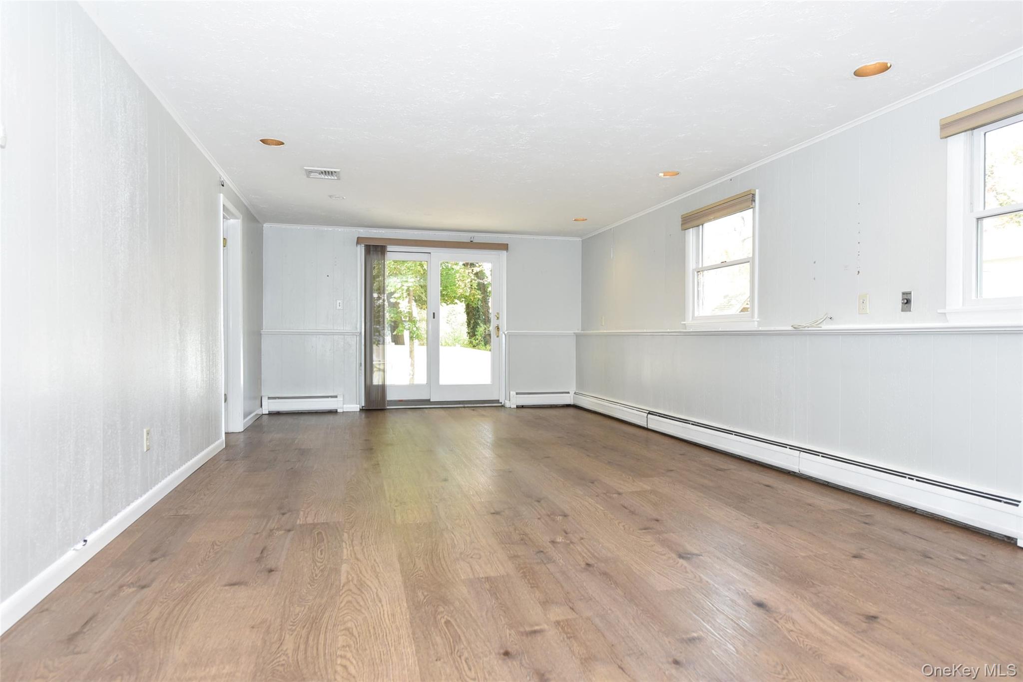 33 Hillcrest Road Suffern, NY 10901 - Photo 23 of 39 Empty room with wood finished floors, crown molding, baseboard heating, healthy amount of natural light, and wainscoting