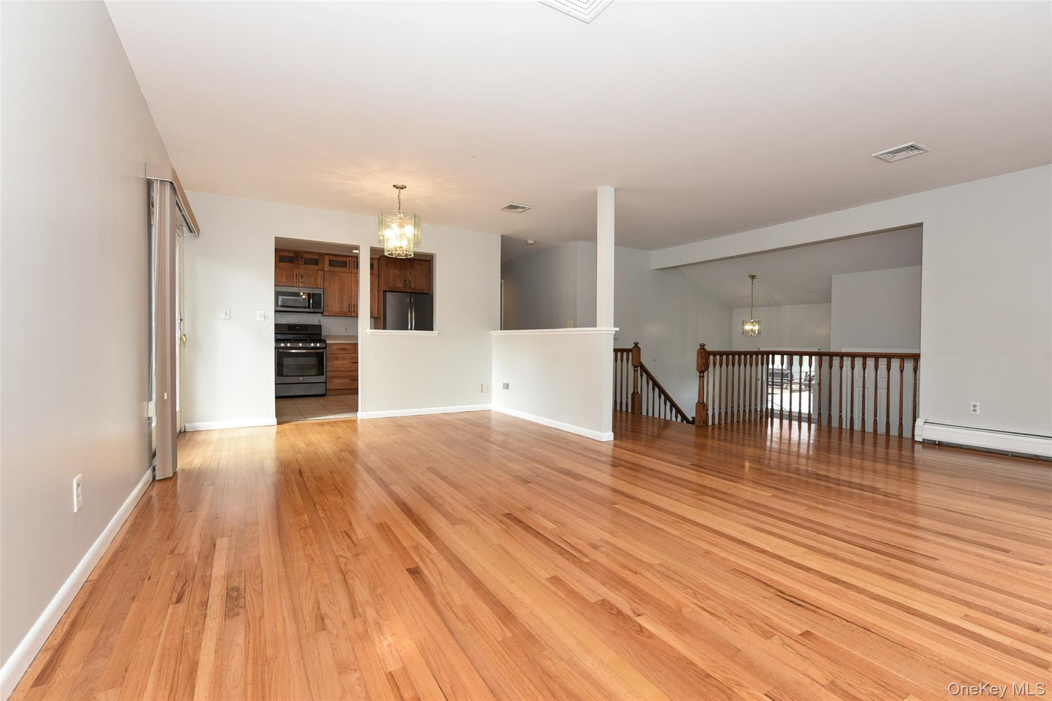 33 Hillcrest Road Suffern, NY 10901 - Photo 9 of 39 Unfurnished living room featuring a chandelier, light wood finished floors, and lofted ceiling