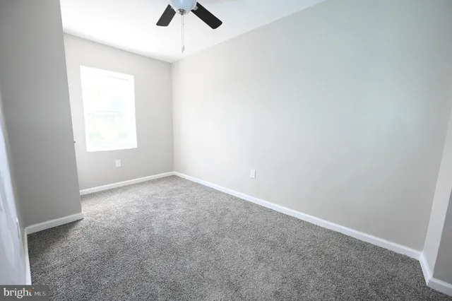 an empty room with a window and a fan