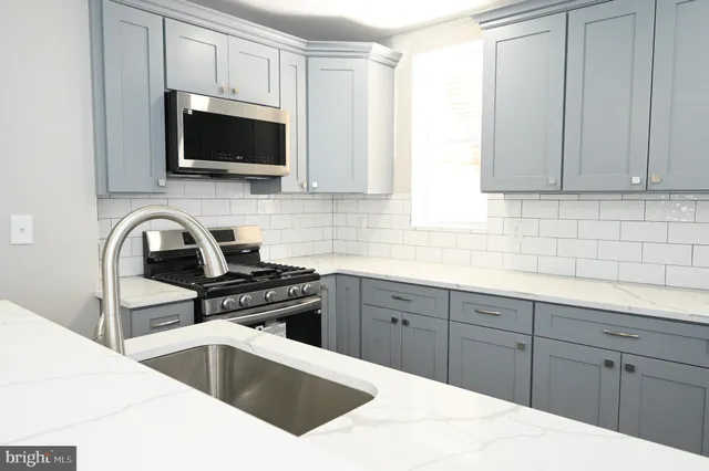 a kitchen with stainless steel appliances white cabinets a sink and a stove