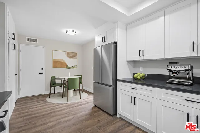 a kitchen with stainless steel appliances granite countertop a refrigerator a stove and white cabinets with wooden floor