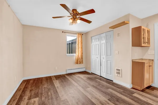 a view of an empty room with window and wooden floor