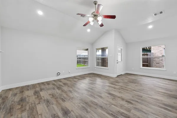 a view of an empty room with chandelier fan and wooden floor