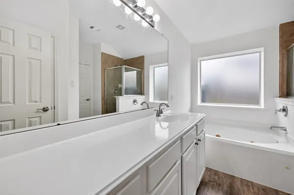 a bathroom with a tub a sink and mirror