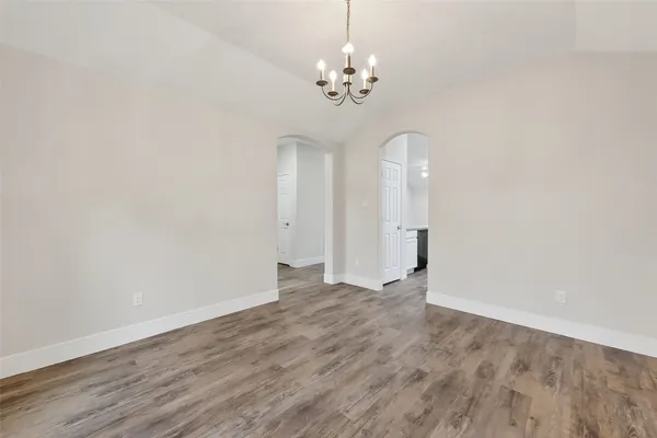 a view of an empty room with wooden floor and chandelier