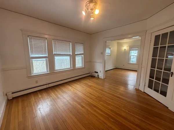 an empty room with wooden floor and windows