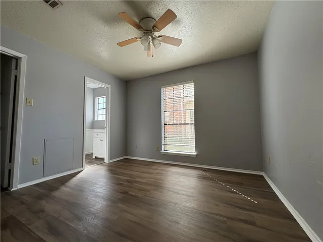 an empty room with wooden floor chandelier fan and windows