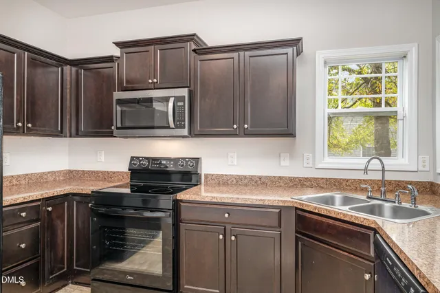 a kitchen with granite countertop a sink stove and microwave