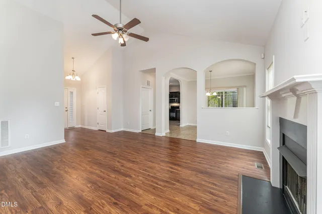 a view of an empty room with a kitchen and a fireplace
