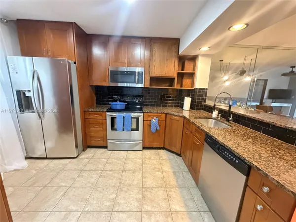 a large kitchen with stainless steel appliances granite countertop a stove a sink dishwasher and a refrigerator