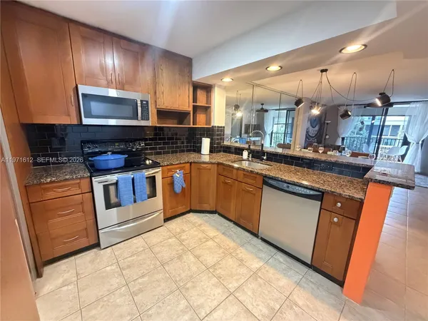 a kitchen with stainless steel appliances granite countertop a stove a sink and a microwave