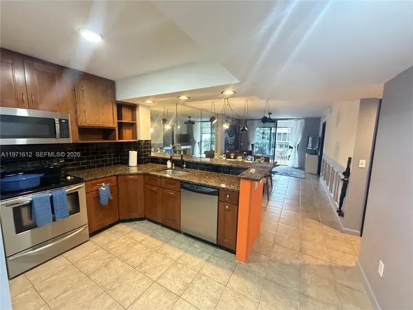 a kitchen with stainless steel appliances granite countertop a stove a sink dishwasher and a refrigerator