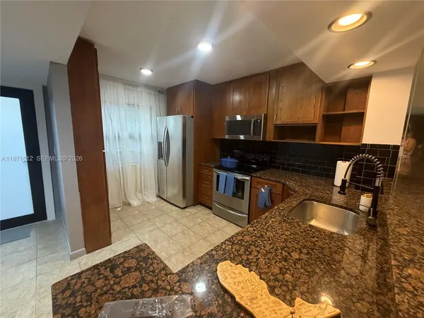 a kitchen with stainless steel appliances granite countertop a refrigerator and a sink