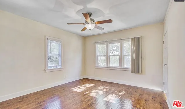 a view of an empty room with wooden floor and a window