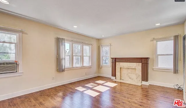 an empty room with windows and fireplace