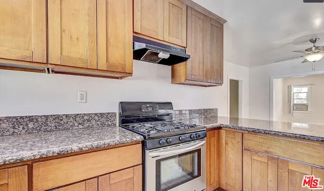 a kitchen with granite countertop cabinets stainless steel appliances and a counter space