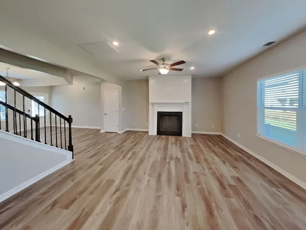 a view of an empty room with wooden floor fireplace and a window