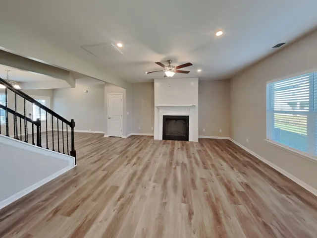 a view of an empty room with wooden floor fireplace and a window