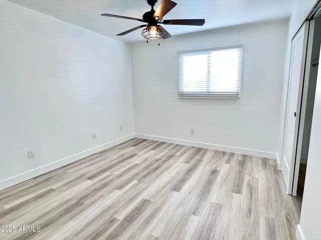 a view of an empty room with window and a ceiling fan