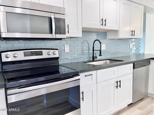 a kitchen with granite countertop white cabinets and sink