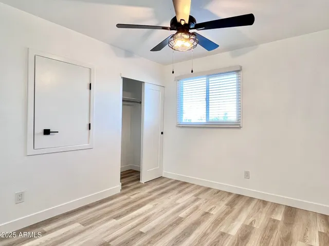 wooden floor in an empty room with a chandelier fan