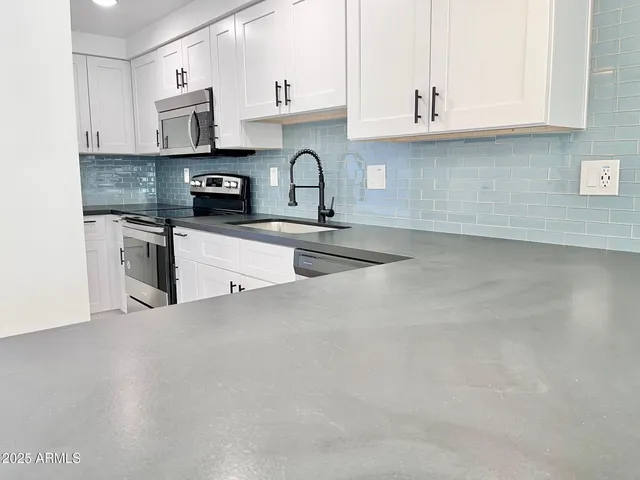 a kitchen with stainless steel appliances granite countertop a sink a stove a microwave and cabinets