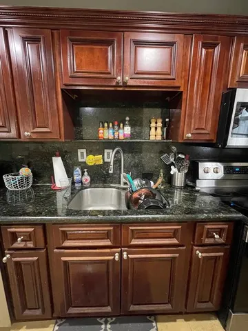 a kitchen with stainless steel appliances granite countertop a stove a sink and a microwave