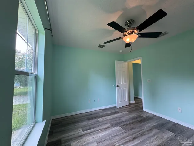 a view of empty room with wooden floor and fan
