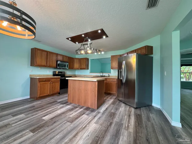 a kitchen with stainless steel appliances granite countertop a stove a sink and a refrigerator