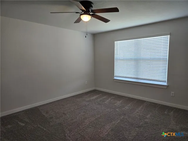an empty room with a window and a fan