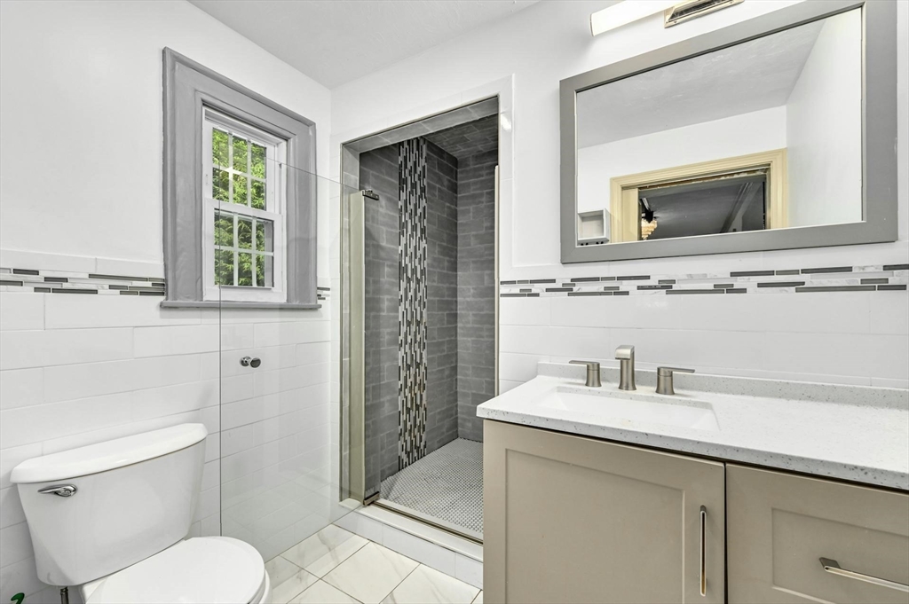 41 Flagg Street Worcester, MA 01602 - Photo 4 of 31 a bathroom with a toilet a sink a mirror a window and vanity