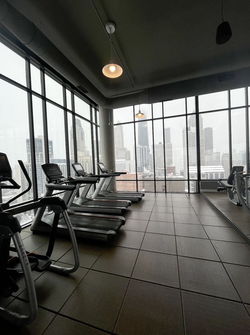 833 North Clark Street, Unit 2408 Chicago, IL 60610 - Photo 13 of 21 a living room with gym equipment and a large window