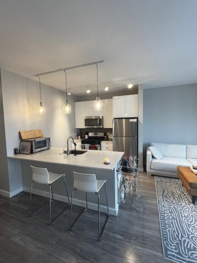 833 North Clark Street, Unit 2408 Chicago, IL 60610 - Photo 2 of 21 a kitchen with a dining table chairs wooden floor and a refrigerator