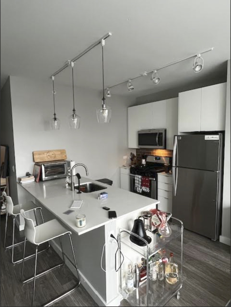 833 North Clark Street, Unit 2408 Chicago, IL 60610 - Photo 4 of 21 a kitchen with a refrigerator a stove a sink and a dining table with wooden floor
