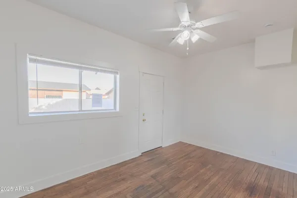 a view of an empty room with window and wooden floor