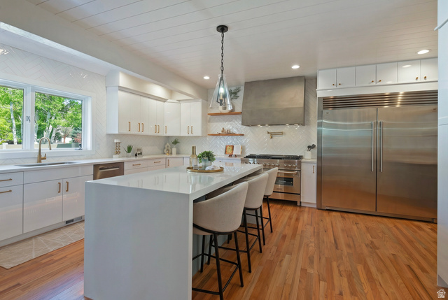 16 Gatehouse Lane Sandy, UT 84092 - Photo 10 of 73 Kitchen with premium appliances, pendant lighting, upgraded cabinetry, a breakfast bar area, and light wood finished floors