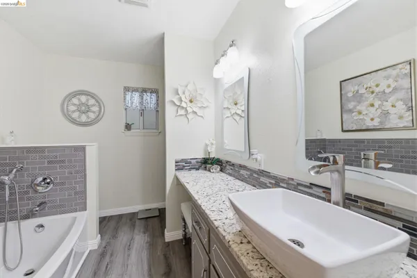 a bathroom with a tub a sink and a mirror