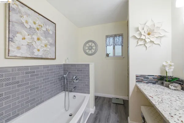 a bathroom with a granite countertop sink a mirror and a bathtub