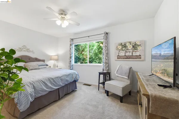 a bedroom with a bed furniture a flat screen tv and a chandelier