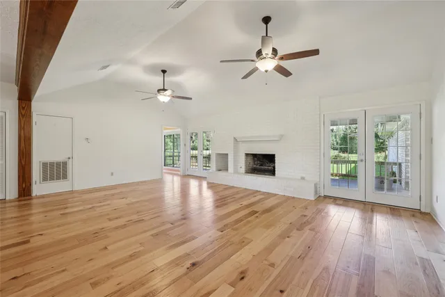 a view of an empty room with wooden floor fireplace and a window