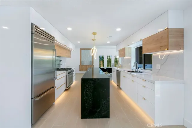 a large kitchen with stainless steel appliances kitchen island a large counter top and a refrigerator