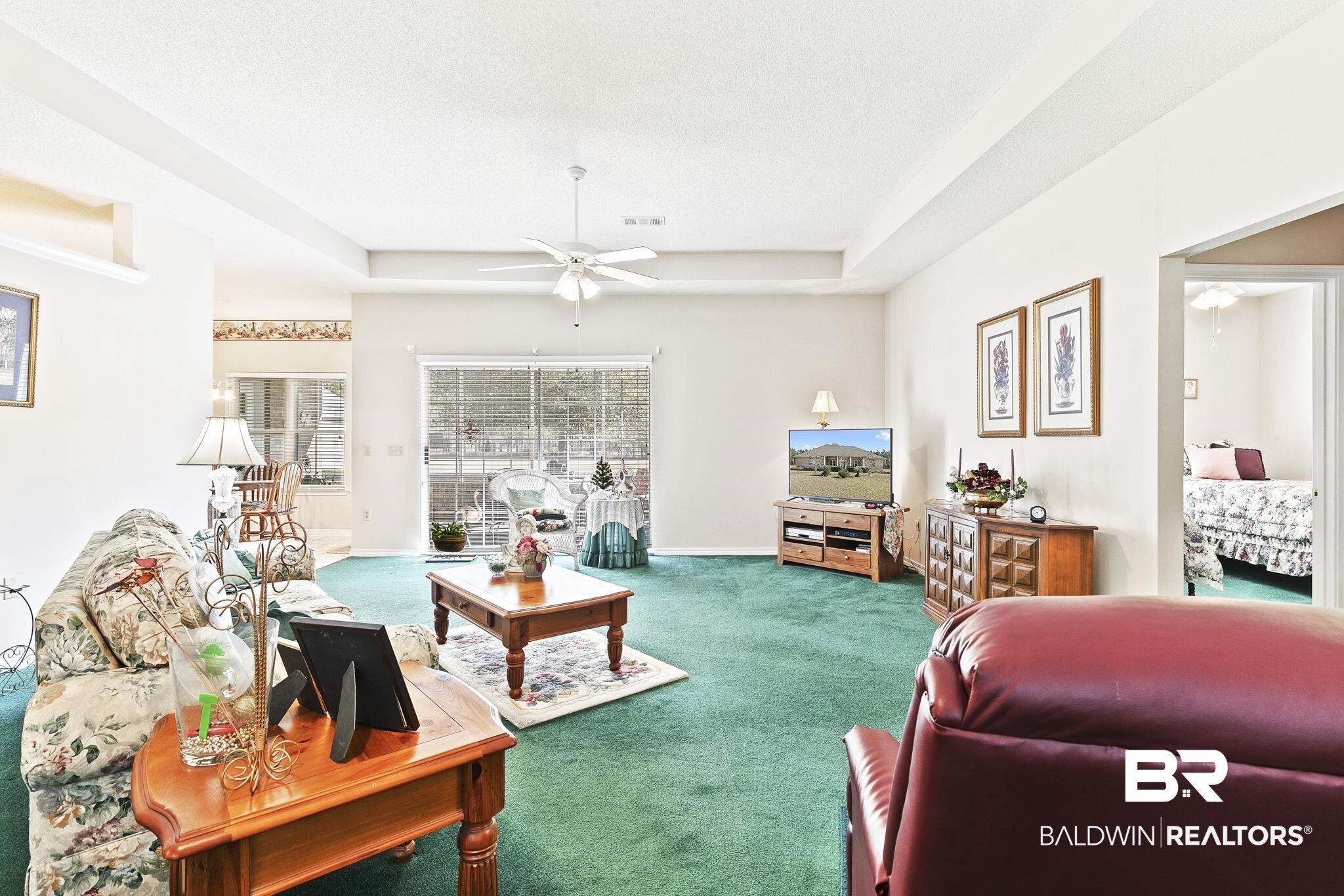 24130 Cowling Road Robertsdale, AL 36567 - Photo 13 of 71 Carpeted living room with ceiling fan, a textured ceiling, and a tray ceiling
